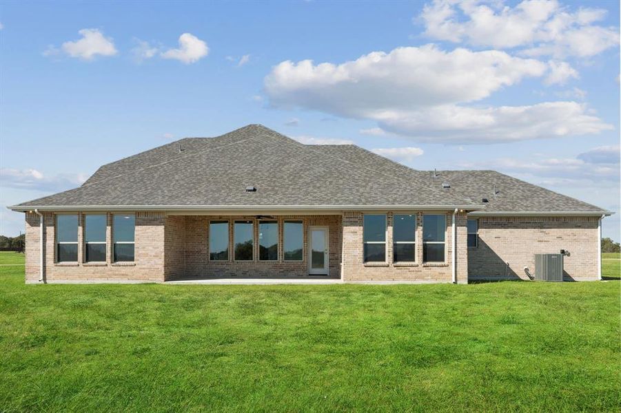 Rear view of house with a lawn, a patio, a shingled roof, and brick siding