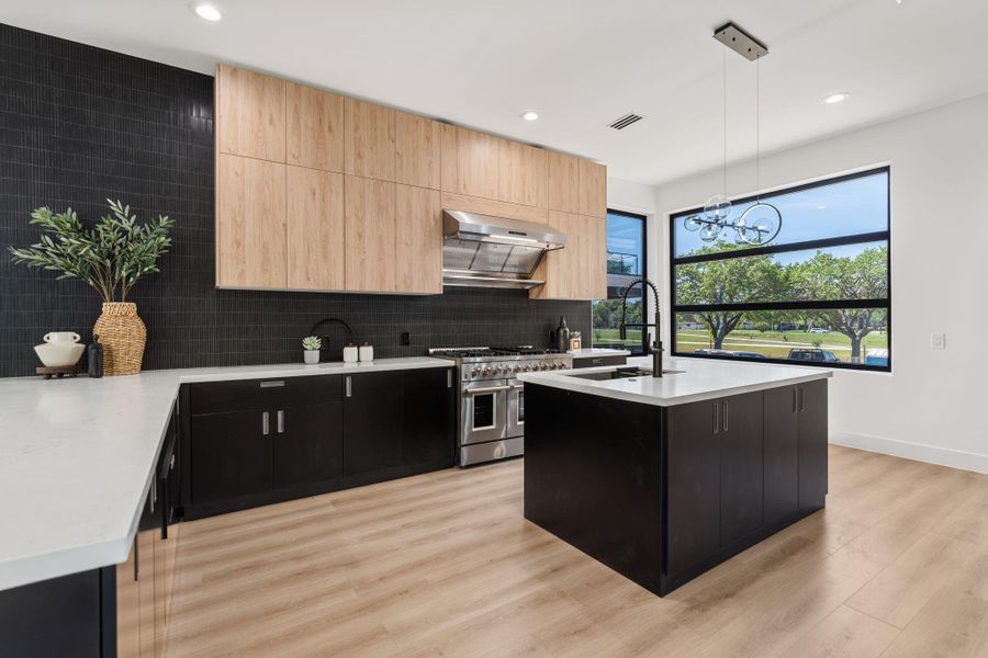 The cooking wall is built for serious use — a Forno multi-burner stainless gas range centered on the wall below a stainless range hood, extensive counter space, and ample storage create a kitchen worth spending time in.