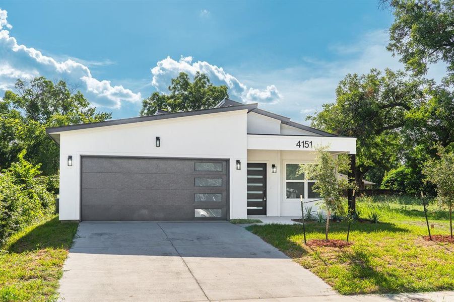 Contemporary house with driveway, stucco siding, an attached garage, and a front lawn Contemporary house with driveway, stucco siding, an attached garage, and a front lawn