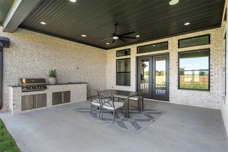 View of patio / terrace with an outdoor kitchen, french doors, outdoor dining area, and a ceiling fan