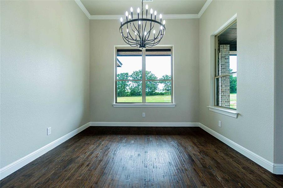 Unfurnished room with dark hardwood / wood-style flooring, crown molding, and a chandelier