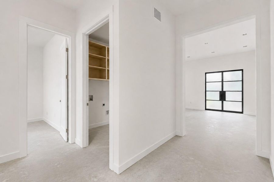 Expansive entryway with light-toned flooring, leading to a room with a large black-framed glass door