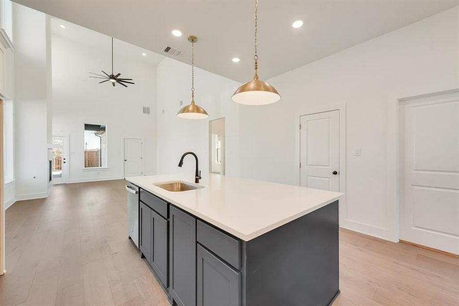 Kitchen featuring light wood-style flooring, pendant lighting, a high ceiling, a center island with sink, and recessed lighting Kitchen featuring light wood-style flooring, pendant lighting, a high ceiling, a center island with sink, and recessed lighting