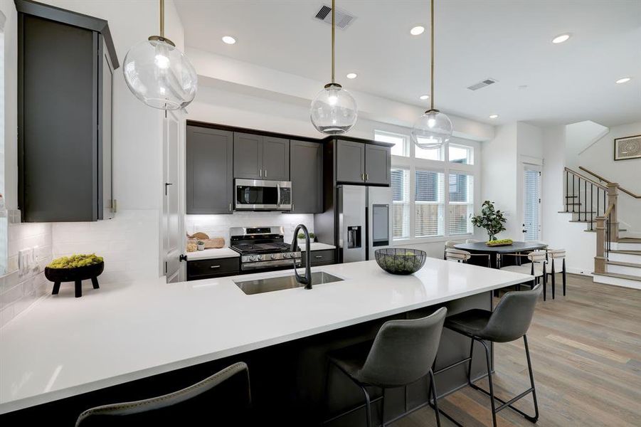 Modern Chef's Kitchen: Sleek cabinetry and high-end appliances set against a backdrop of bright, open-plan living space, complete with elegant lighting and a welcoming breakfast bar.