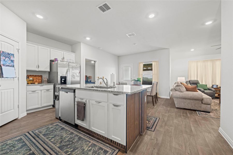 A well-lit kitchen with granite countertops and stainless steel appliances flows seamlessly into the inviting living area.