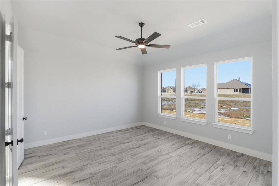Spare room with light wood-type flooring, a residential view, and ceiling fan