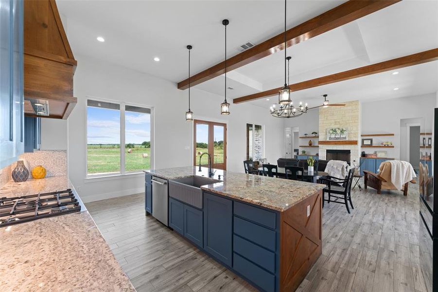 Spacious kitchen featuring a large island with granite countertops, an integrated farmhouse sink, and a stainless steel dishwasher