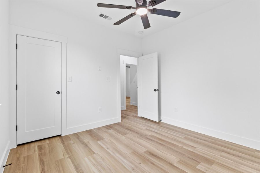 Secondary bedroom with light wood-type flooring and a ceiling fan