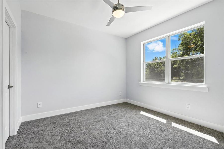 Empty room featuring dark carpet and ceiling fan