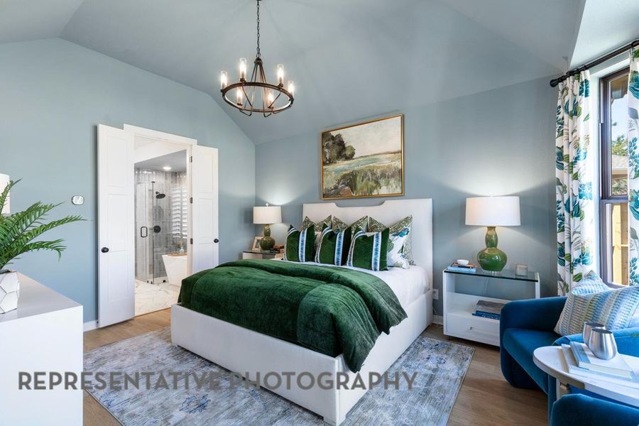 Bedroom featuring lofted ceiling, a chandelier, wood finished floors, and ensuite bath Bedroom featuring lofted ceiling, a chandelier, wood finished floors, and ensuite bath