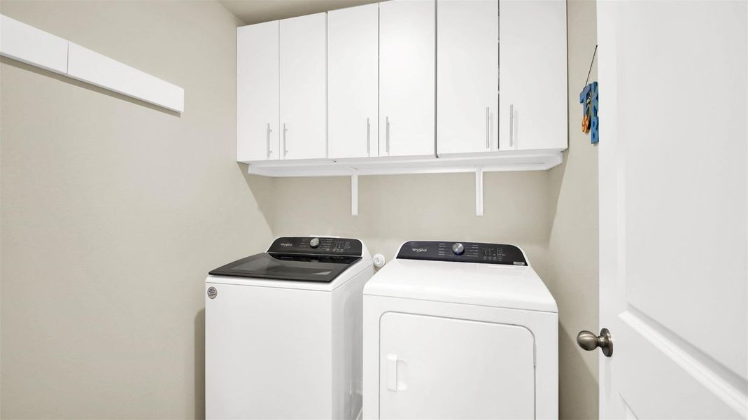 Dedicated laundry area featuring white upper cabinetry, a coordinating white wall-mounted shelf, and a built-in wall rack