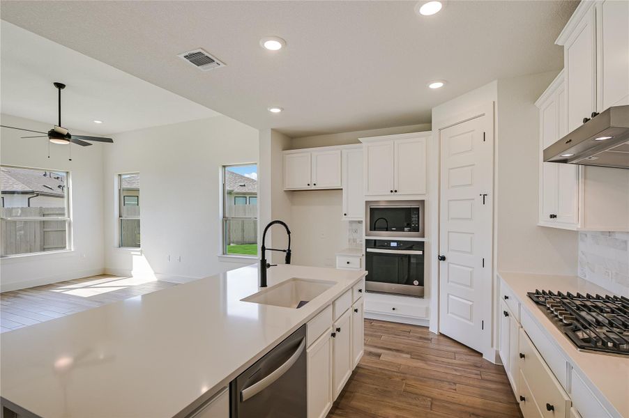 Kitchen featuring dark wood finished floors, stainless steel appliances, decorative backsplash, white cabinetry, and recessed lighting