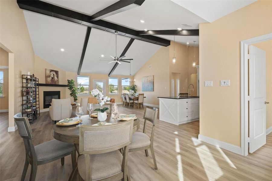 Open-concept living space featuring vaulted ceilings with exposed beams, wood-finish flooring, a built-in fireplace, and recessed lighting Open-concept living space featuring vaulted ceilings with exposed beams, wood-finish flooring, a built-in fireplace, and recessed lighting