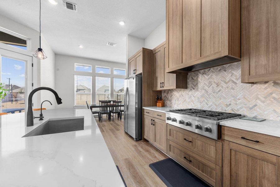 Kitchen with light wood-style flooring, stainless steel appliances and stylish backsplash