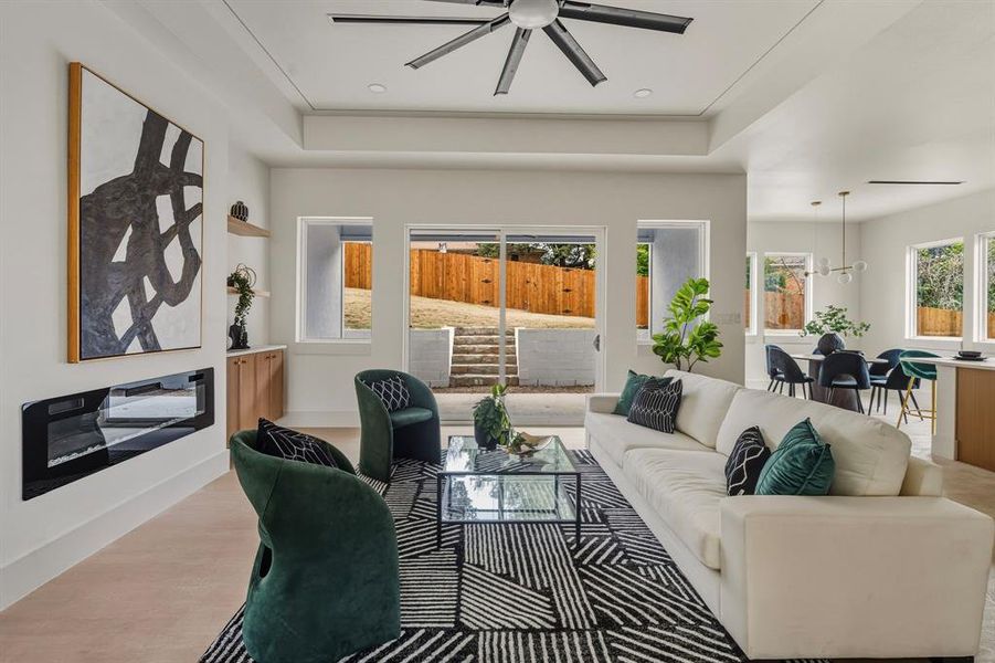 Living room with a ceiling fan, wood finished floors, and a tray ceiling