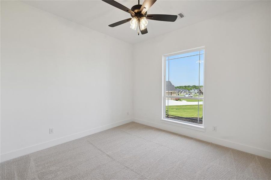 Carpeted spare room featuring ceiling fan