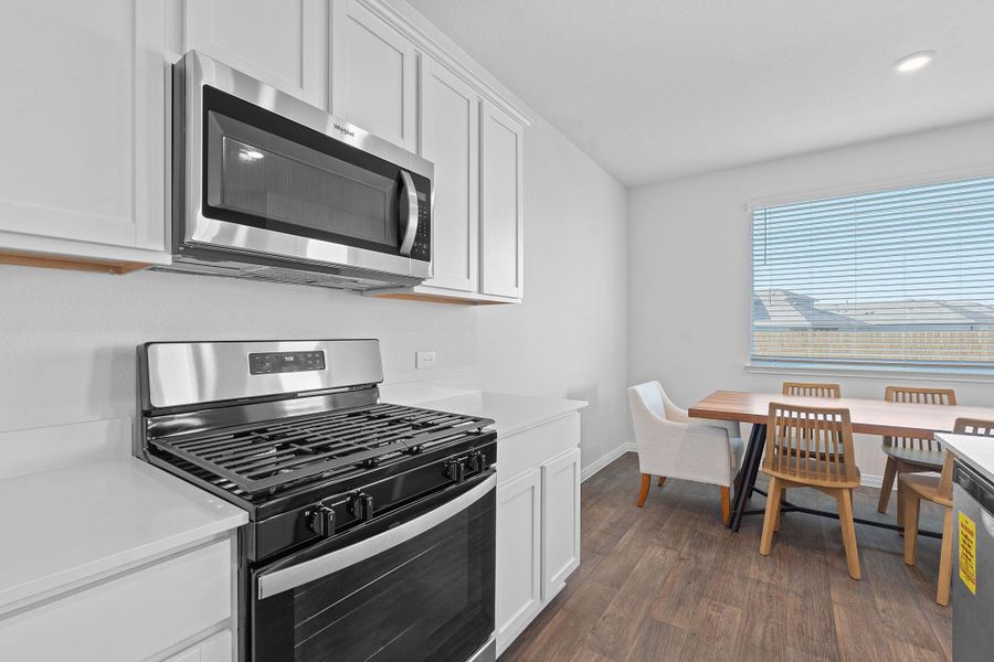 Kitchen featuring stainless steel appliances, white cabinetry, and dark wood-style flooring Kitchen featuring stainless steel appliances, white cabinetry, and dark wood-style flooring