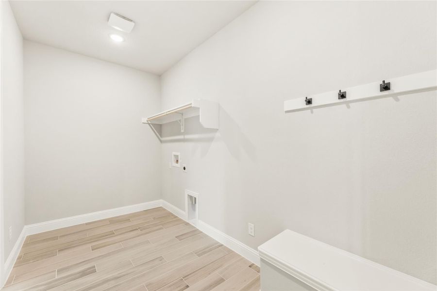 Laundry and mudroom area with white shelving, coat hooks, bench, and light wood-look tile floors Laundry and mudroom area with white shelving, coat hooks, bench, and light wood-look tile floors