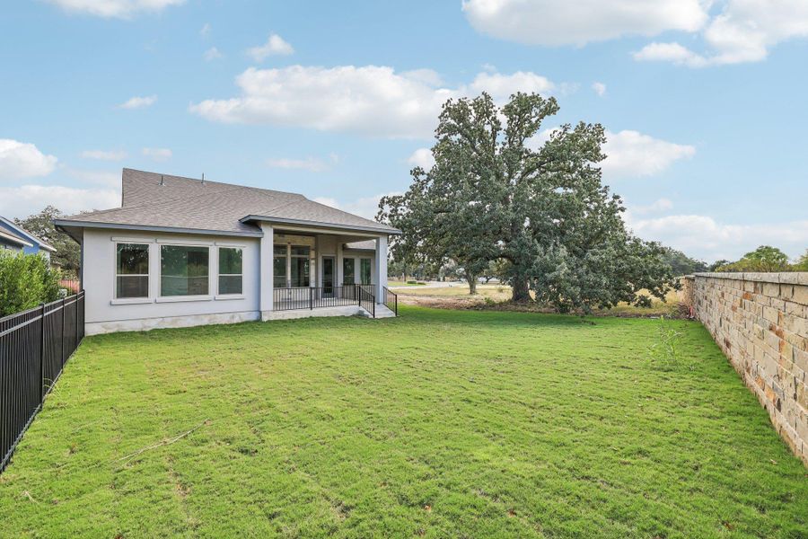 Rear view of property featuring roof with shingles, a fenced backyard, and a patio area