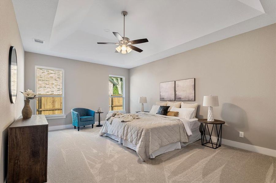 Bedroom featuring a tray ceiling, ceiling fan, and light carpet Bedroom featuring a tray ceiling, ceiling fan, and light carpet