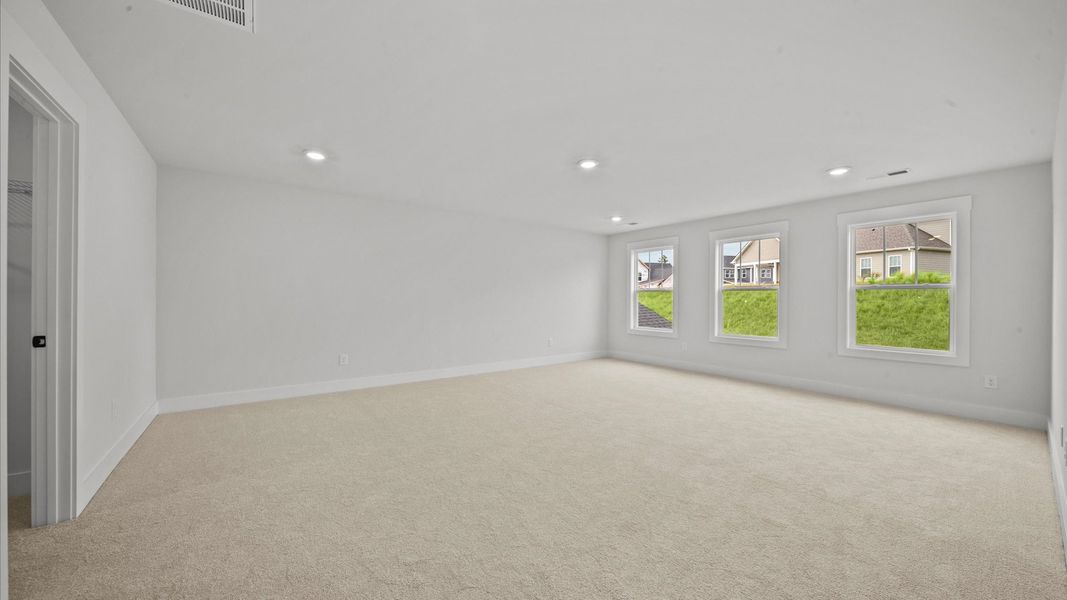 Elegant bedroom retreat featuring soft carpet and oversized windows that create a bright, welcoming space