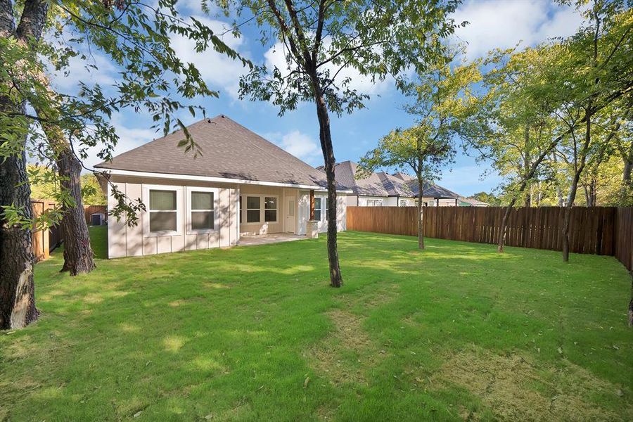 Rear view of property with a patio area, a fenced backyard, and roof with shingles