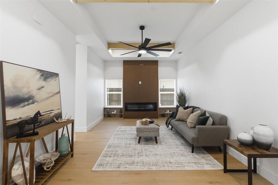 Spacious living area featuring light wood-finish flooring and a vaulted ceiling with exposed wood beams