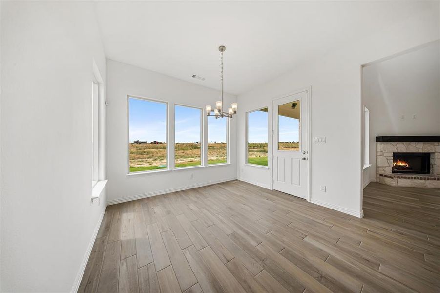 Unfurnished dining area with light wood-style flooring, a fireplace, and a chandelier Unfurnished dining area with light wood-style flooring, a fireplace, and a chandelier