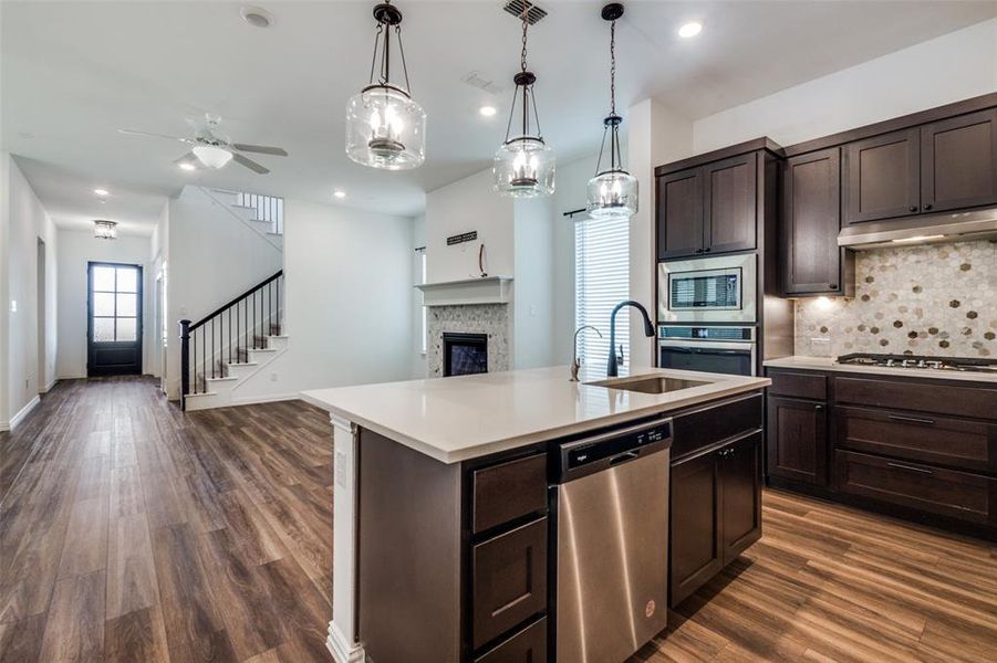 Kitchen with pendant lighting, sink, ceiling fan, an island with sink, and appliances with stainless steel finishes