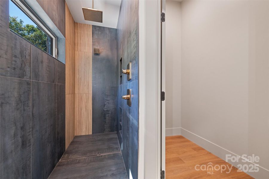 Dreamy shower with multiple shower heads and large closet in primary bathroom