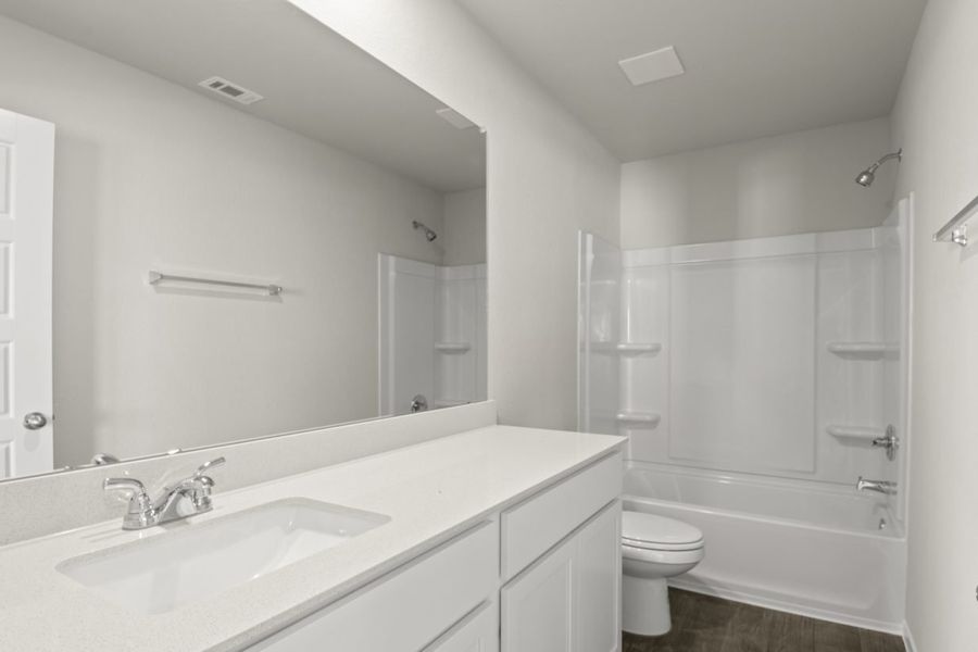 Image of a bathroom with white cabinets, a dual white vanity, a large mirror and a white shower with a tub
