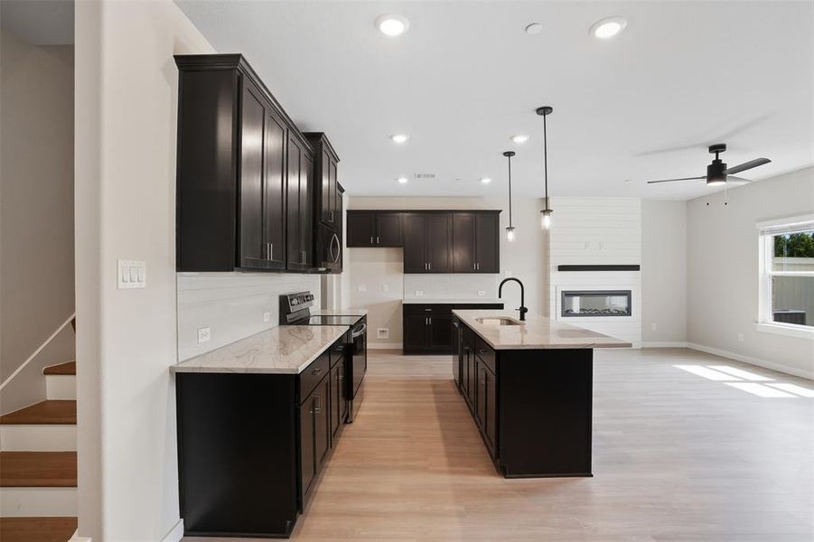 Kitchen featuring light stone countertops, black electric range, recessed lighting, light wood finished floors, and pendant lighting Kitchen featuring light stone countertops, black electric range, recessed lighting, light wood finished floors, and pendant lighting