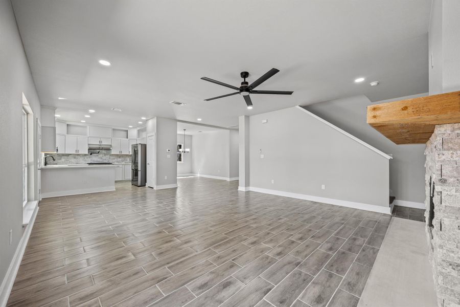 Unfurnished living room featuring ceiling fan, wood tiled floors, recessed lighting, stairway, and a fireplace Unfurnished living room featuring ceiling fan, wood tiled floors, recessed lighting, stairway, and a fireplace