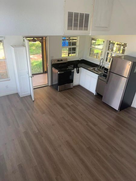 A well-equipped kitchen features sleek appliances, dark countertops, and durable flooring.