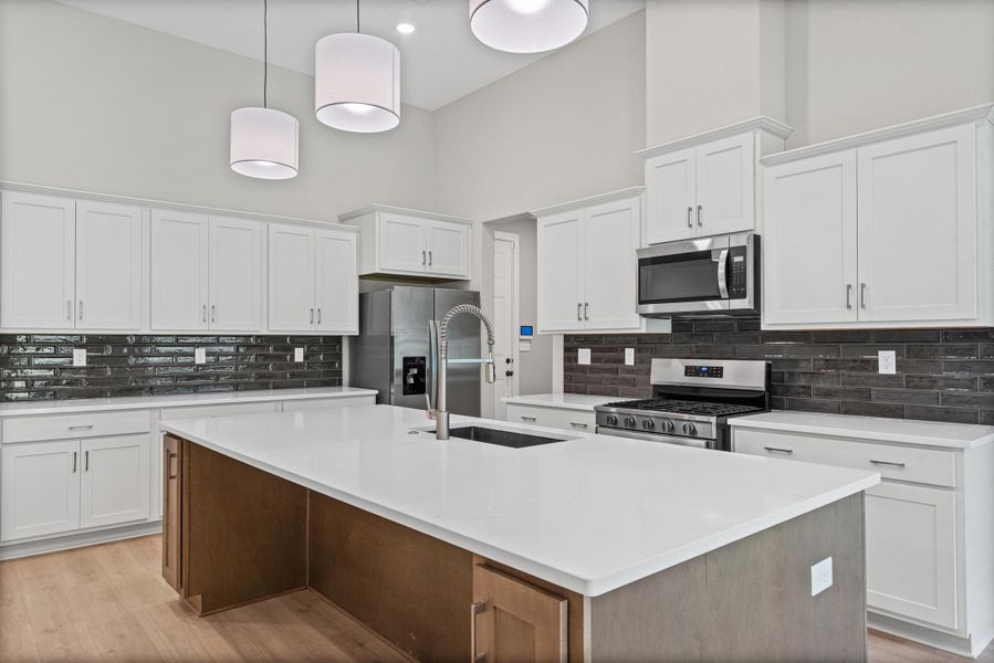 Kitchen featuring a large central island with a white countertop and integrated sink Kitchen featuring a large central island with a white countertop and integrated sink
