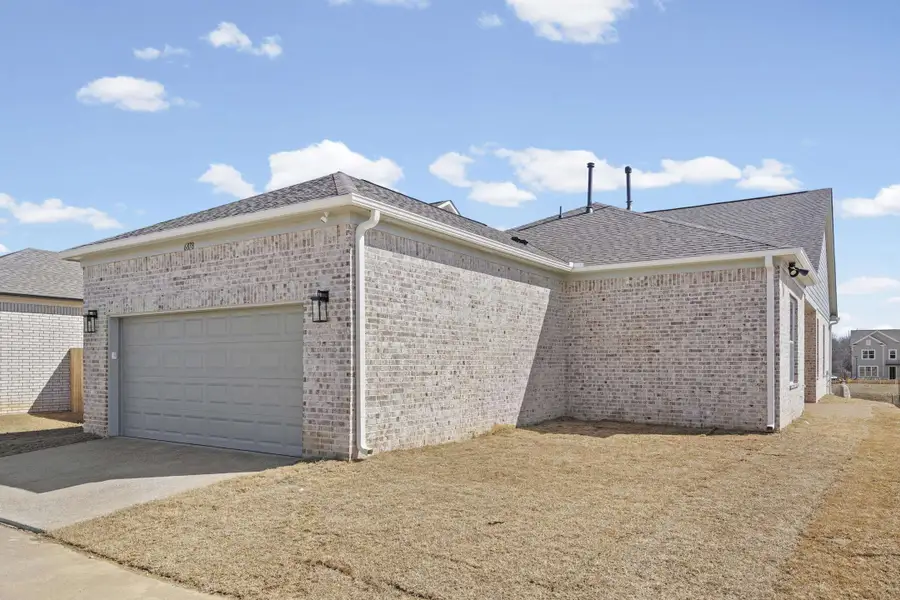 View of property exterior featuring a garage, a shingled roof, driveway, and brick siding