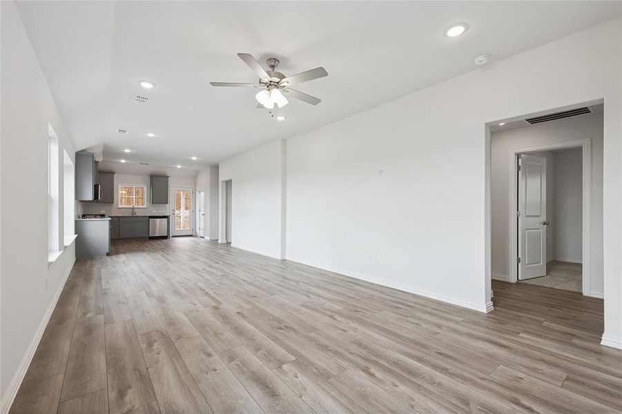 Unfurnished living room with ceiling fan, sink, and light hardwood / wood-style floors