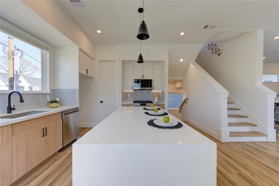 Natural light floods this stunning kitchen with views of East River overlooking the sink! This kitchen features European style white oak and white slim shaker soft-close cabinetry, beautiful custom tile backsplash, white quartz with a 2 inch thick waterfall island, and large walk-in corner pantry.