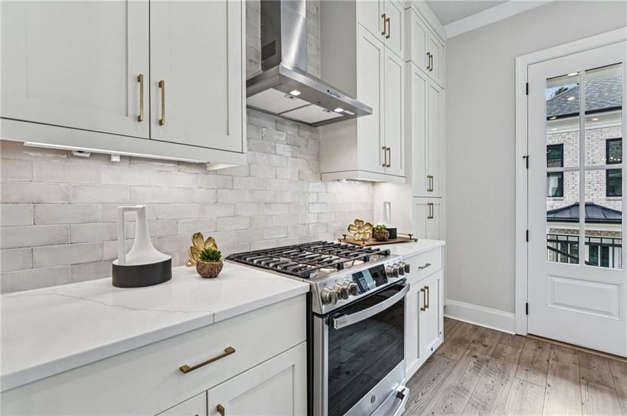Warm and welcoming light colors in kitchen:  Calacatta Miraggio Gold quartz, Rice color backsplash, Carerra White Bell cabinets blend nicely with lighter colored flooring
