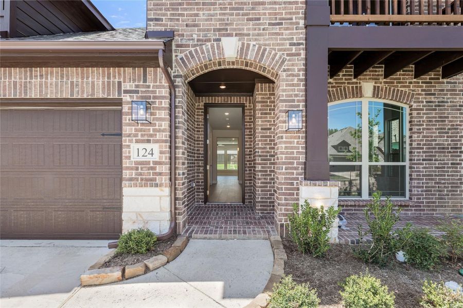 Brick home exterior with arched front entry, garage door, and stone accents at number 124