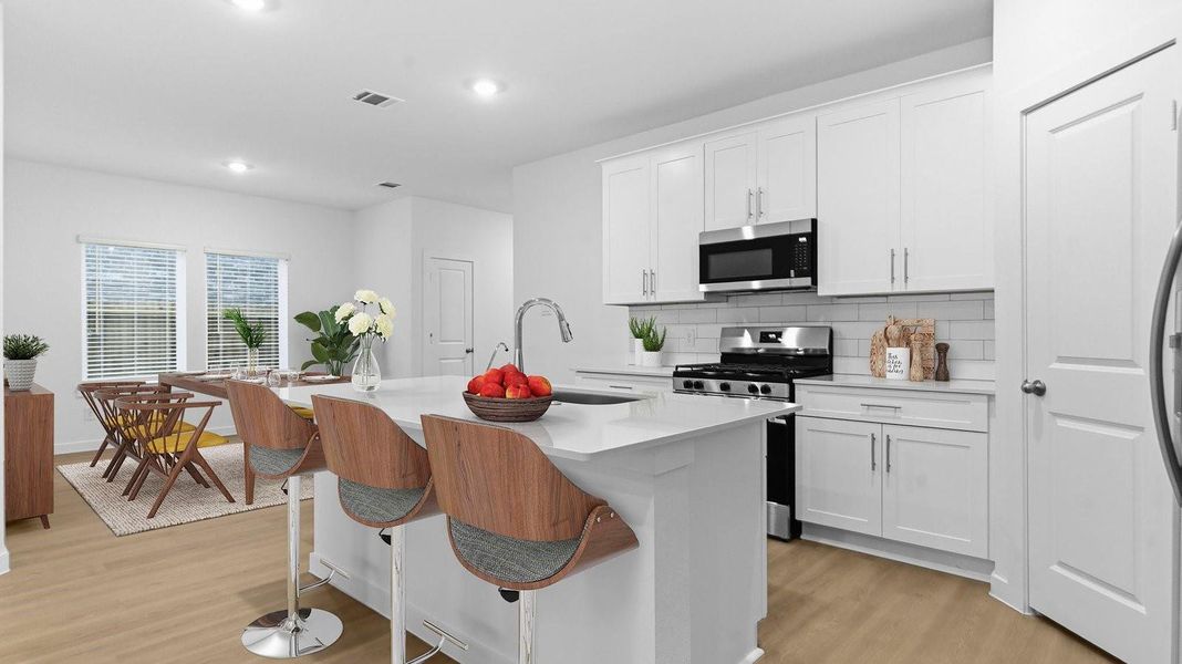 Bright and spacious kitchen with granite countertops, stainless steel appliances, and an island with bar seating. Bright and spacious kitchen with granite countertops, stainless steel appliances, and an island with bar seating.