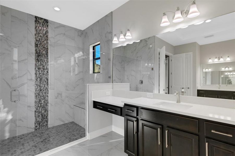 Primary bath shower with gorgeous tile detail and frameless shower door.