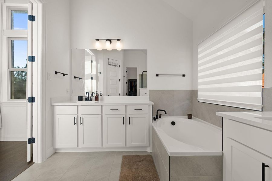 Luxurious soaking tub and dual vanity set in a bright, modern primary bathroom with high ceilings. Luxurious soaking tub and dual vanity set in a bright, modern primary bathroom with high ceilings.