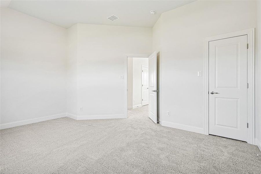 Spare room featuring light colored carpet and vaulted ceiling