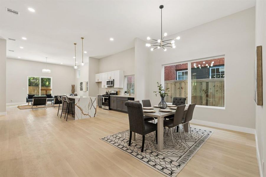 Expansive open-concept space featuring light wood-finish flooring, vaulted ceilings, and recessed lighting Expansive open-concept space featuring light wood-finish flooring, vaulted ceilings, and recessed lighting