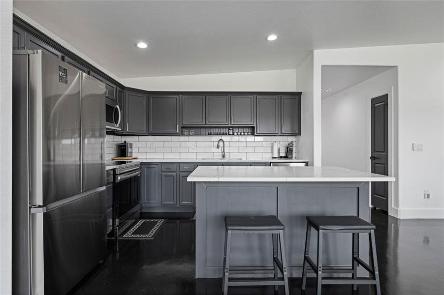 Kitchen featuring stainless steel appliances, lofted ceiling, a kitchen island, and backsplash