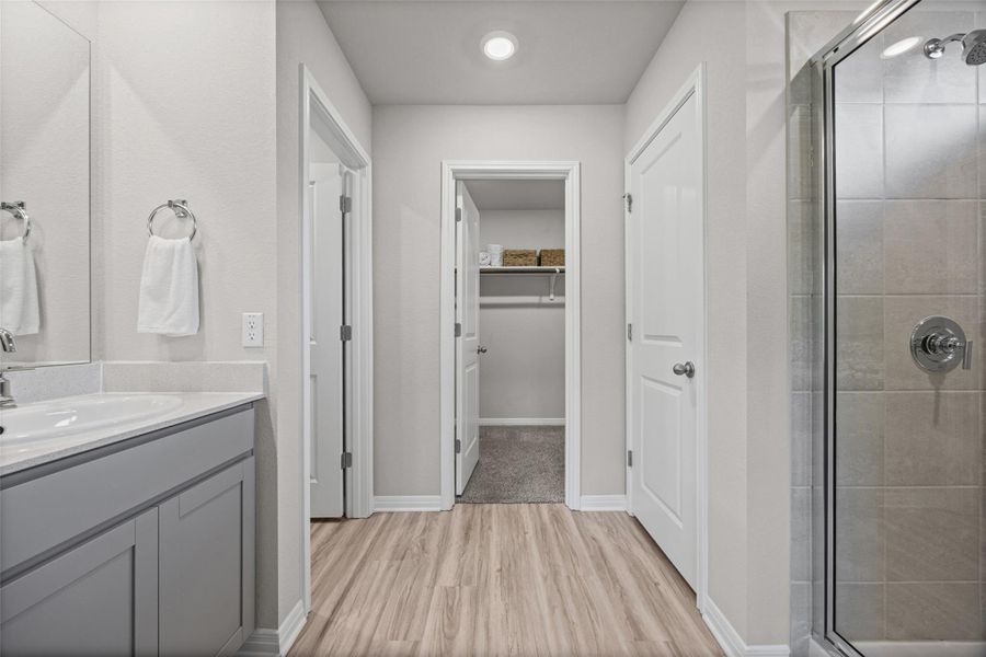 Smooth wood-look flooring leads directly from the vanity area to an adjacent walk-in closet.