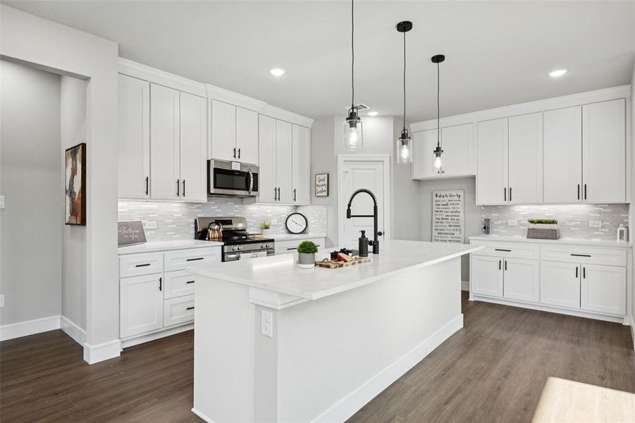 Kitchen with white cabinetry, stainless steel appliances, decorative backsplash, a kitchen island with sink, and recessed lighting