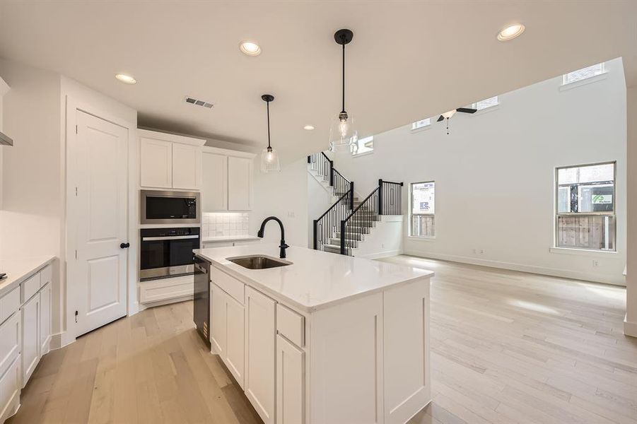 Kitchen featuring recessed lighting, stainless steel appliances, light wood-style floors, white cabinets, and tasteful backsplash Kitchen featuring recessed lighting, stainless steel appliances, light wood-style floors, white cabinets, and tasteful backsplash