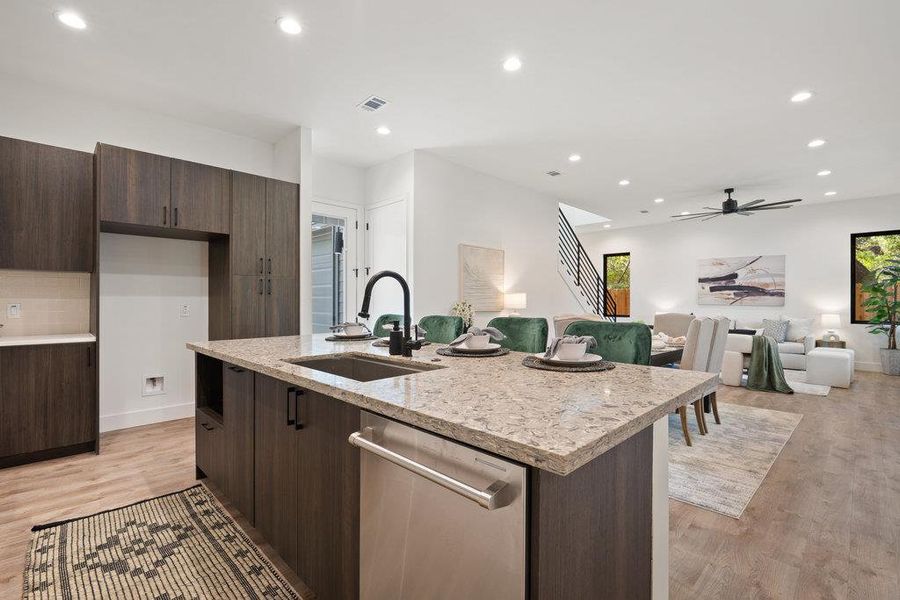 Kitchen featuring dark brown cabinetry, recessed lighting, modern cabinets, open floor plan, and light stone counters
